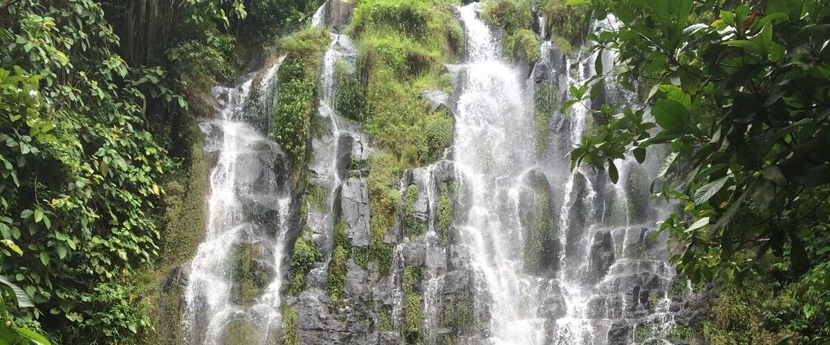 A multi-tiered waterfall surrounded by lush greenery.