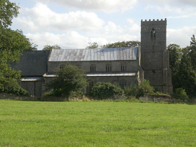 A stone church with a bell tower and a metal roof.