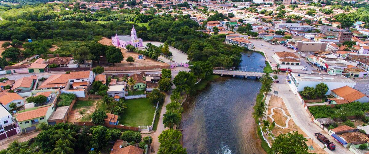 A river flowing through a town with a prominent pink church and a bridge.