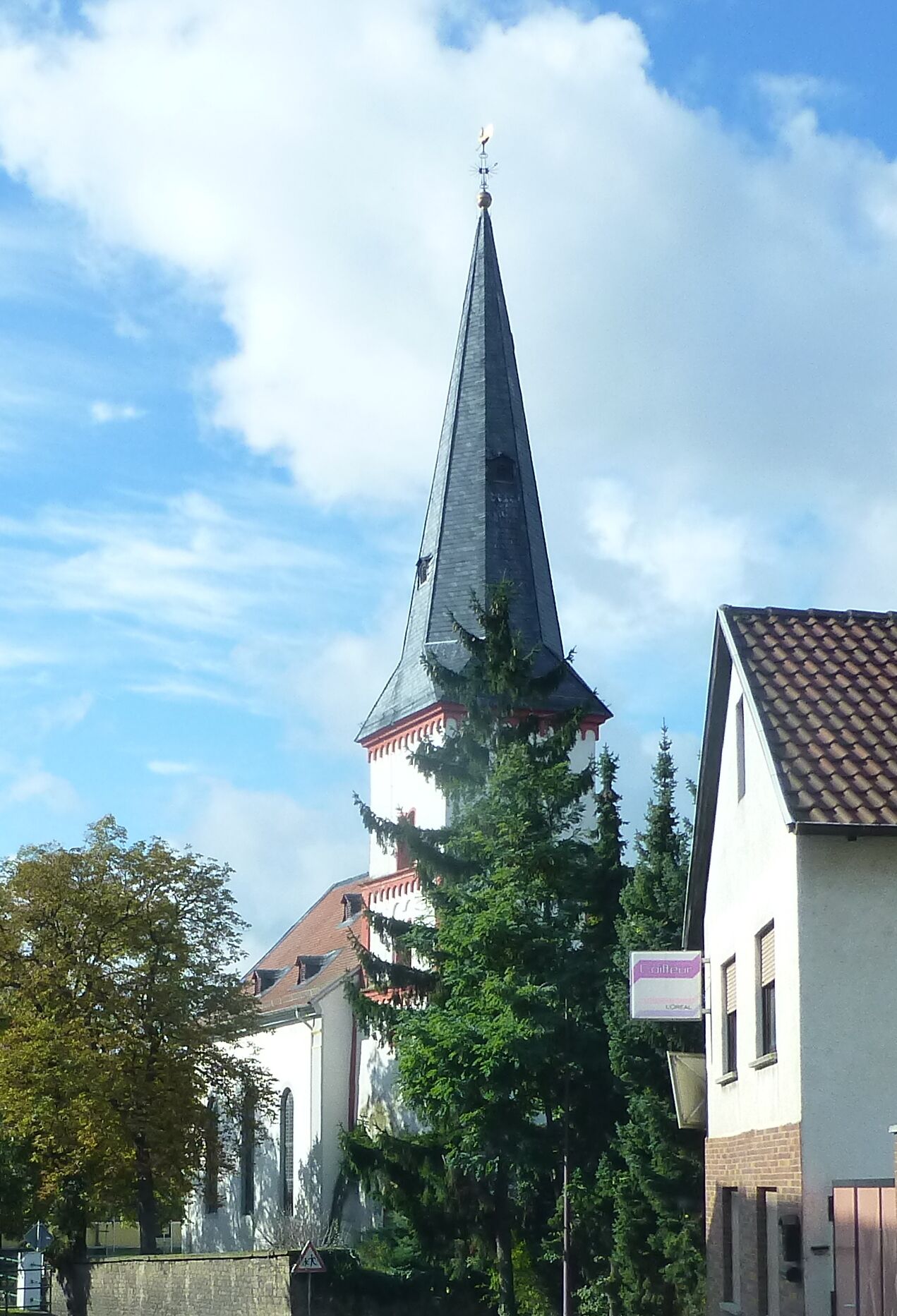 A church with a tall, pointed steeple and a weather vane on top.