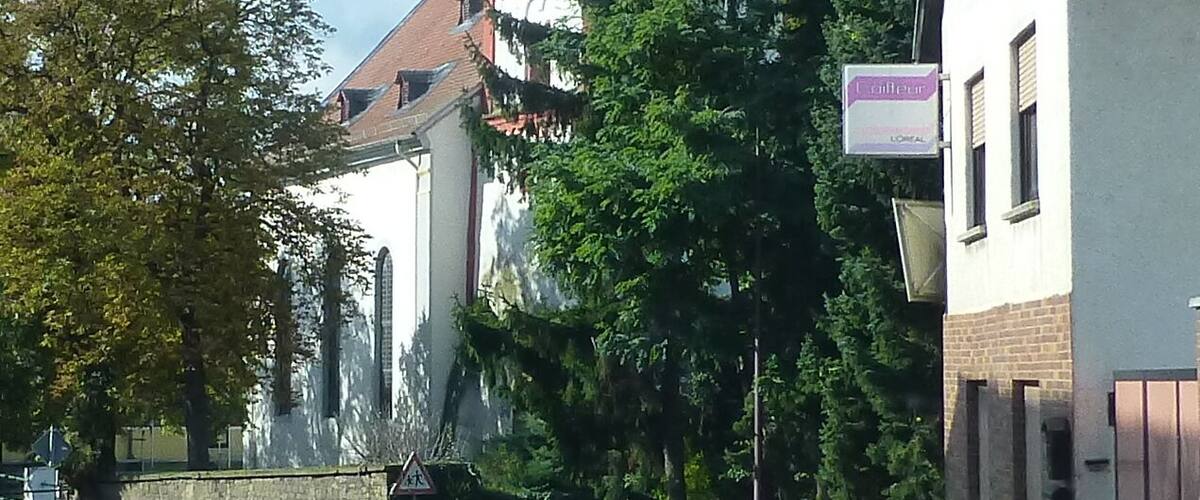 A church with a tall, pointed steeple and a weather vane on top.