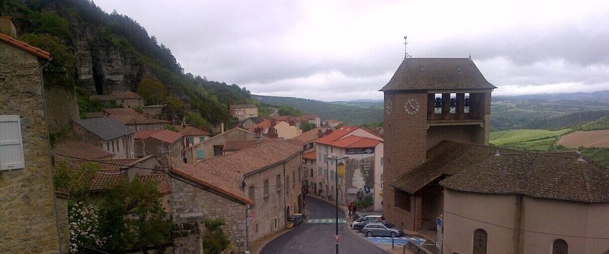 A town with stone buildings, a clock tower, and a winding road.