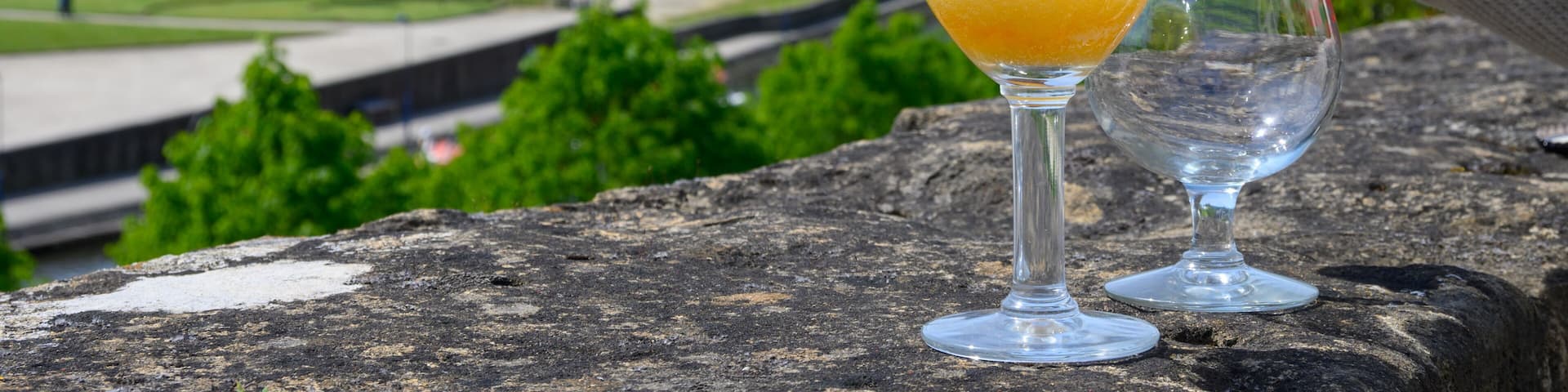 Pouring of blond strong Belgian abbey beer in to glass in sunny day with nice view on old town Bouillon, Belgium