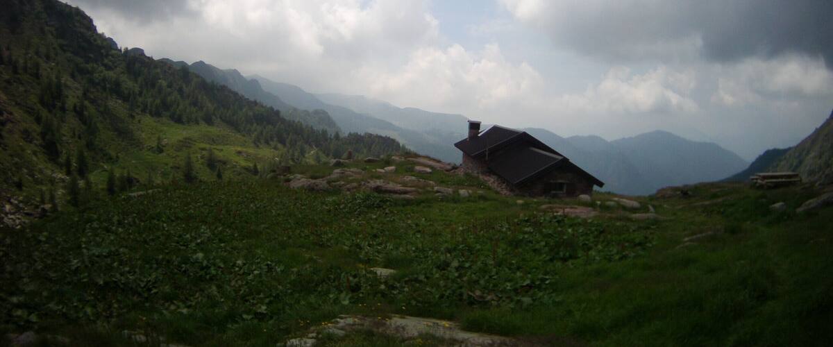 A house in a mountainous area with green fields and rocky terrain.