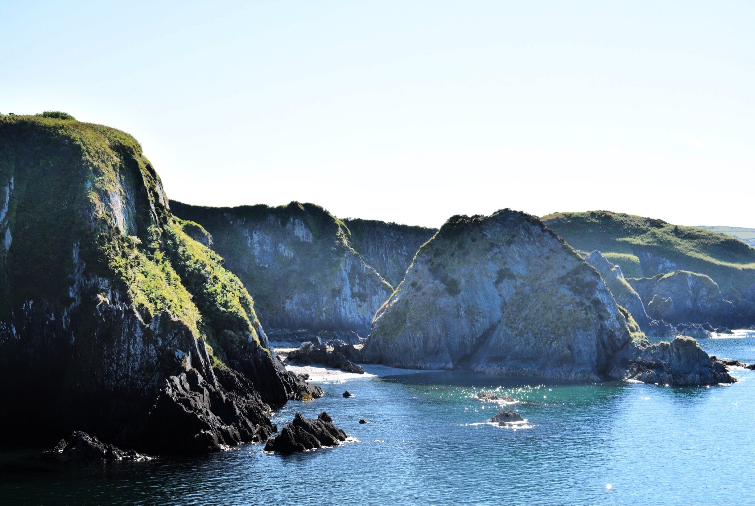 A coastal landscape with rocky cliffs and calm sea.