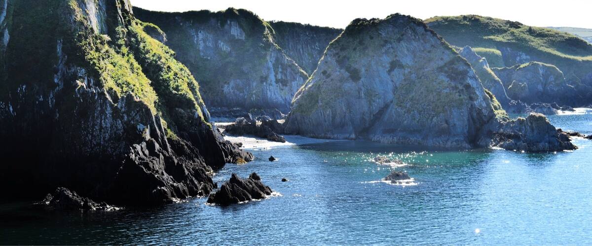 A coastal landscape with rocky cliffs and calm sea.