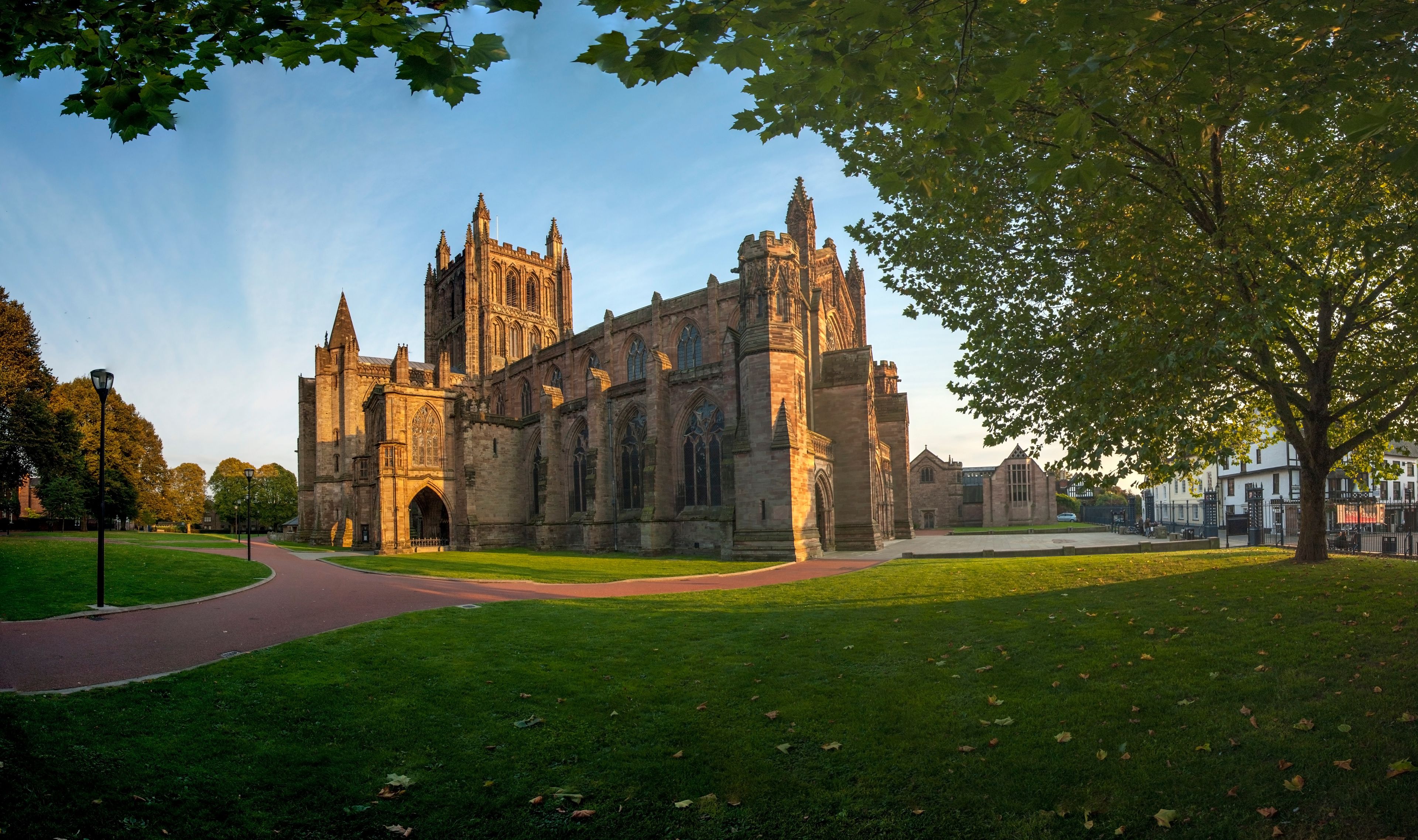 A large historic cathedral with intricate Gothic architecture, surrounded by a well-maintained lawn and a pathway leading to the entrance.