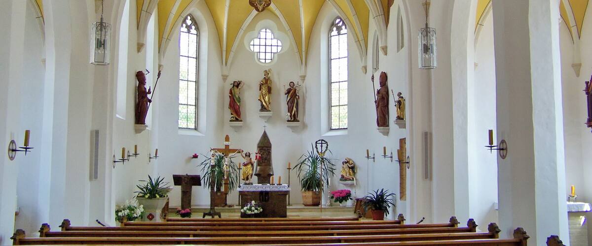A church interior with a crucifix, arched ceilings, and religious statues.