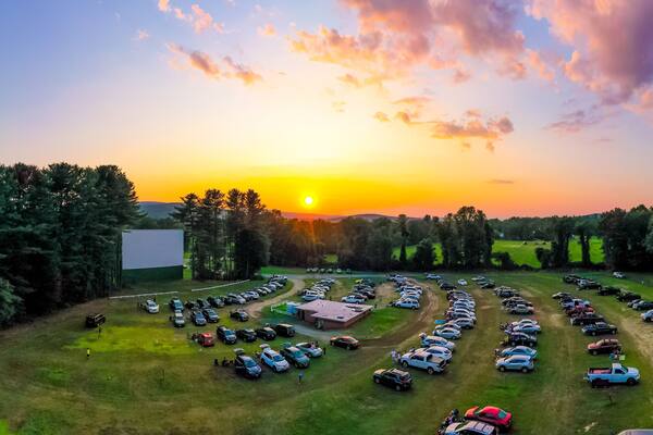 Panorama of outdoor drive-in movie theater at sunset with cars parked in field. Aerial photo taken at Northfield Drive-In.