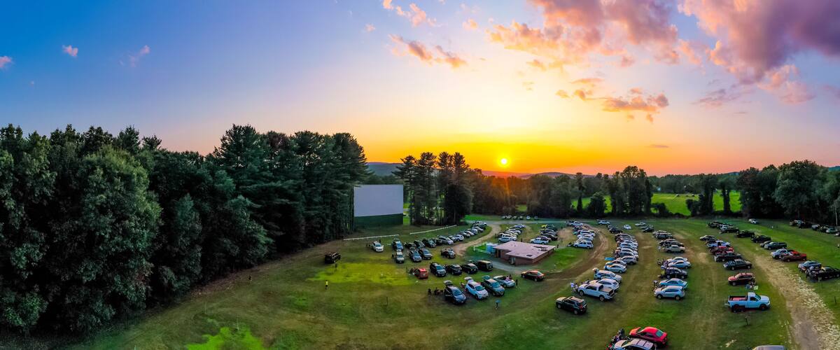 A parking lot with numerous cars and a sunset in the background.