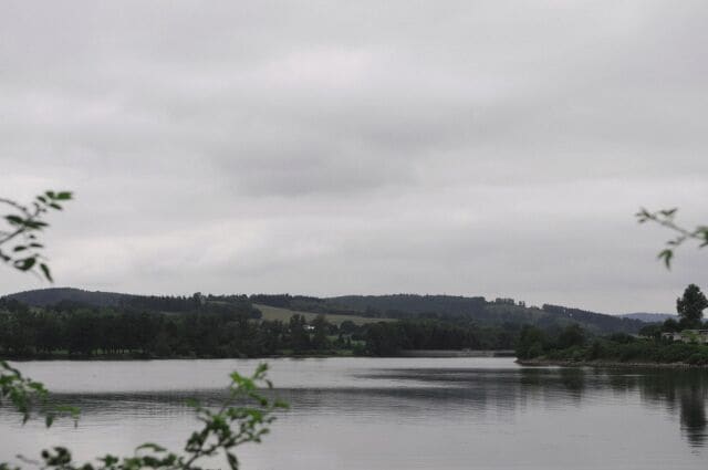 A calm lake with a forested hill in the background.