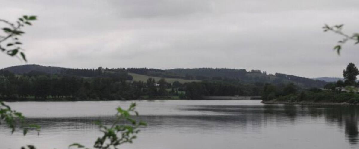 A calm lake with a forested hill in the background.