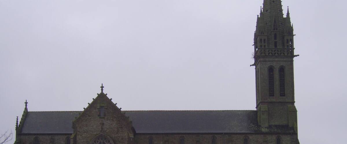 A large stone church with a tall tower and a large arched window.