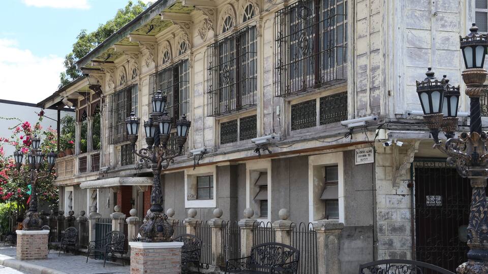 A historic building with ornate architecture, including decorative iron railings and street lamps.