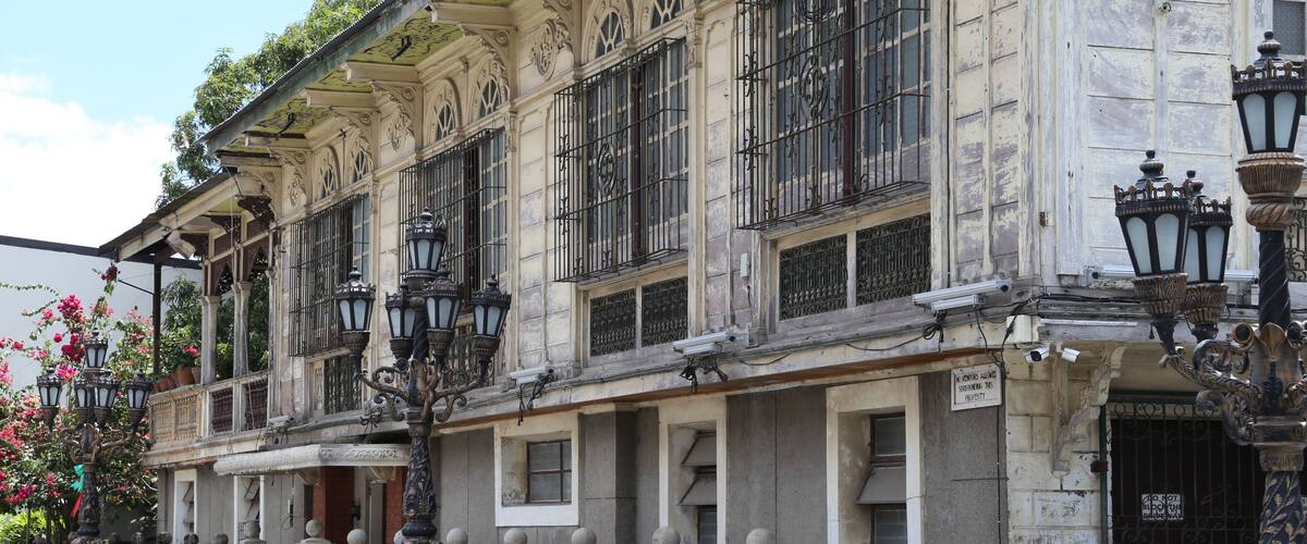 A historic building with ornate architecture, including decorative iron railings and street lamps.
