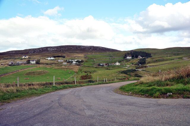 A rural road winding through a hilly landscape with scattered houses and fields.