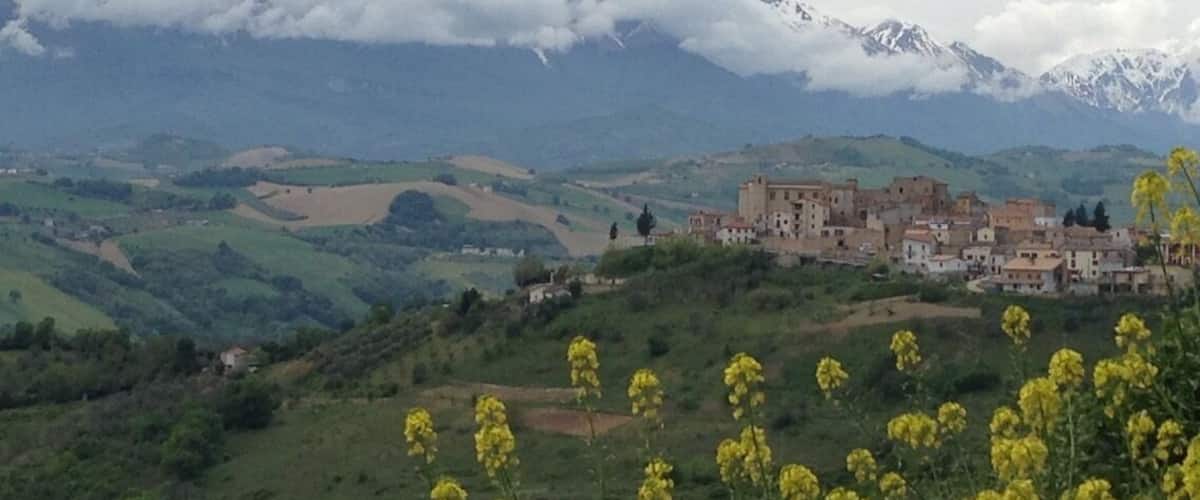 A village nestled in a valley with mountains in the background.