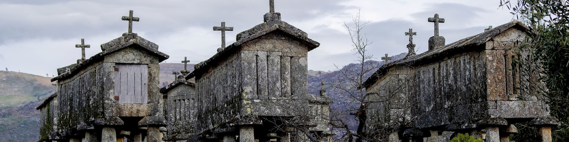 A row of stone crosses atop a hill with a cloudy sky.