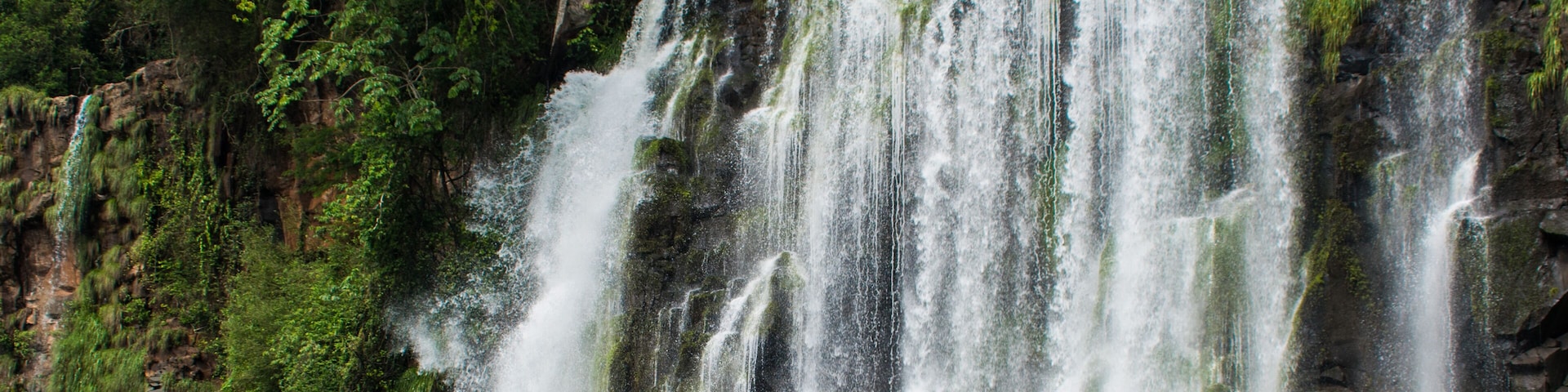 Una cascada imponente que se precipita por un acantilado rocoso rodeado de vegetación exuberante.