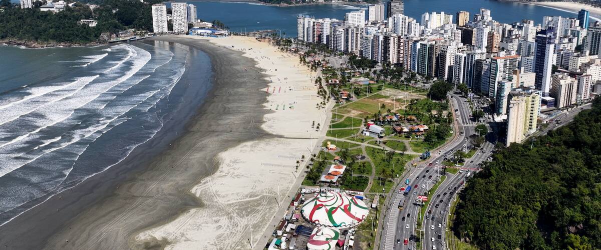 A coastal city with a beach, high-rise buildings, and a mountainous backdrop.
