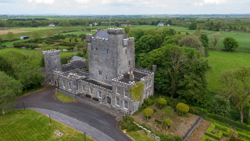 A large stone castle surrounded by lush green fields and trees.