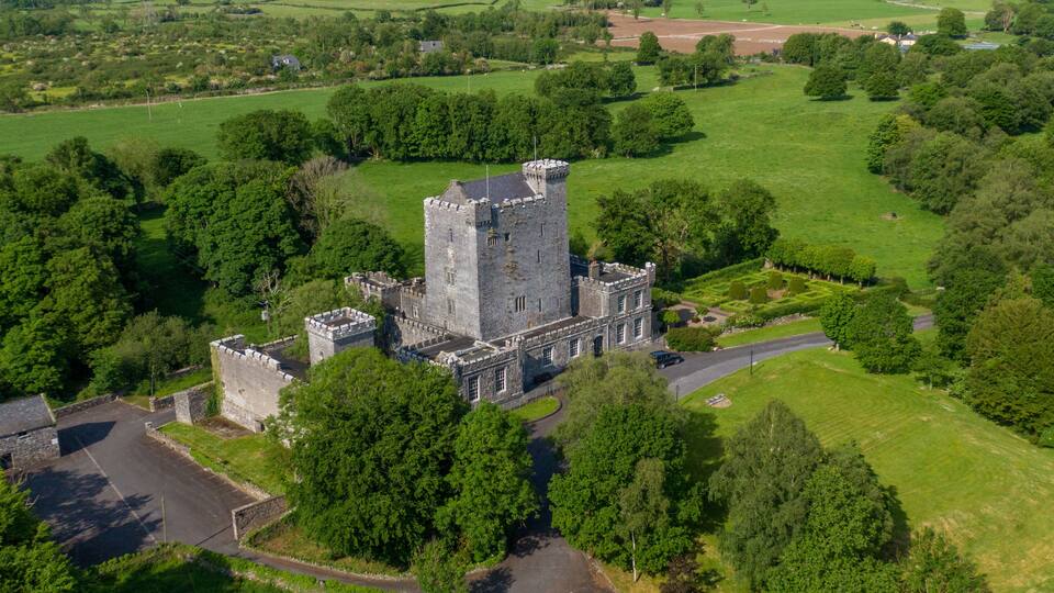 An aerial view of a historic castle surrounded by lush greenery and fields.