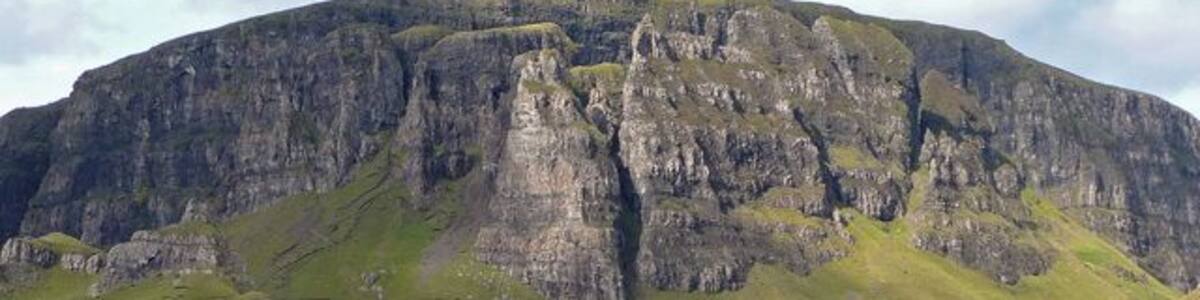 Une montagne escarpée, avec de hautes falaises et une vallée verdoyante.