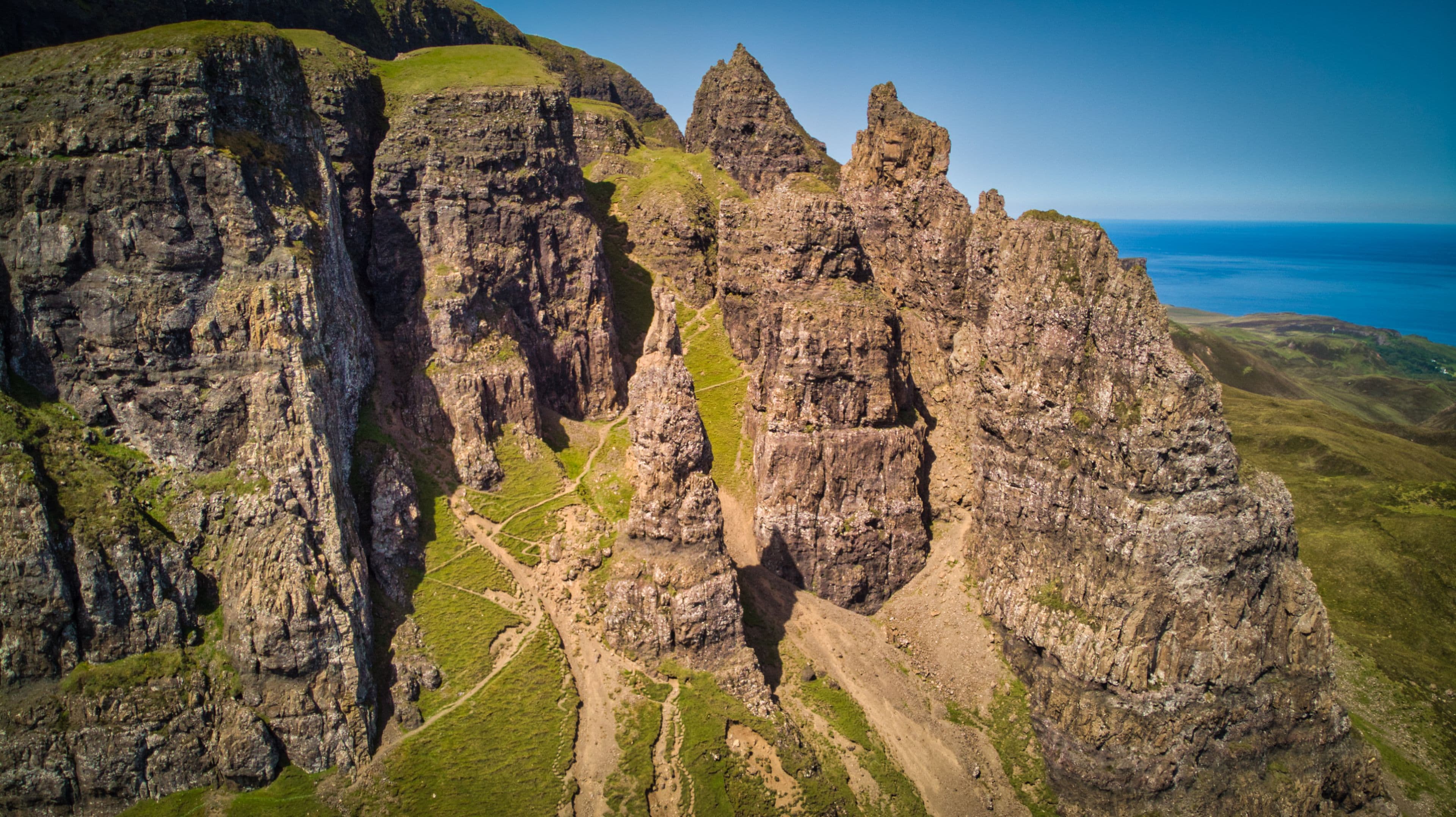 A rugged cliffside with a narrow canyon and a clear view of the ocean.