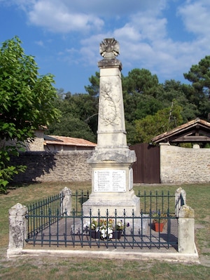 Un monumento de piedra con una lista de nombres, rodeado por una cerca de metal y plantas en macetas.