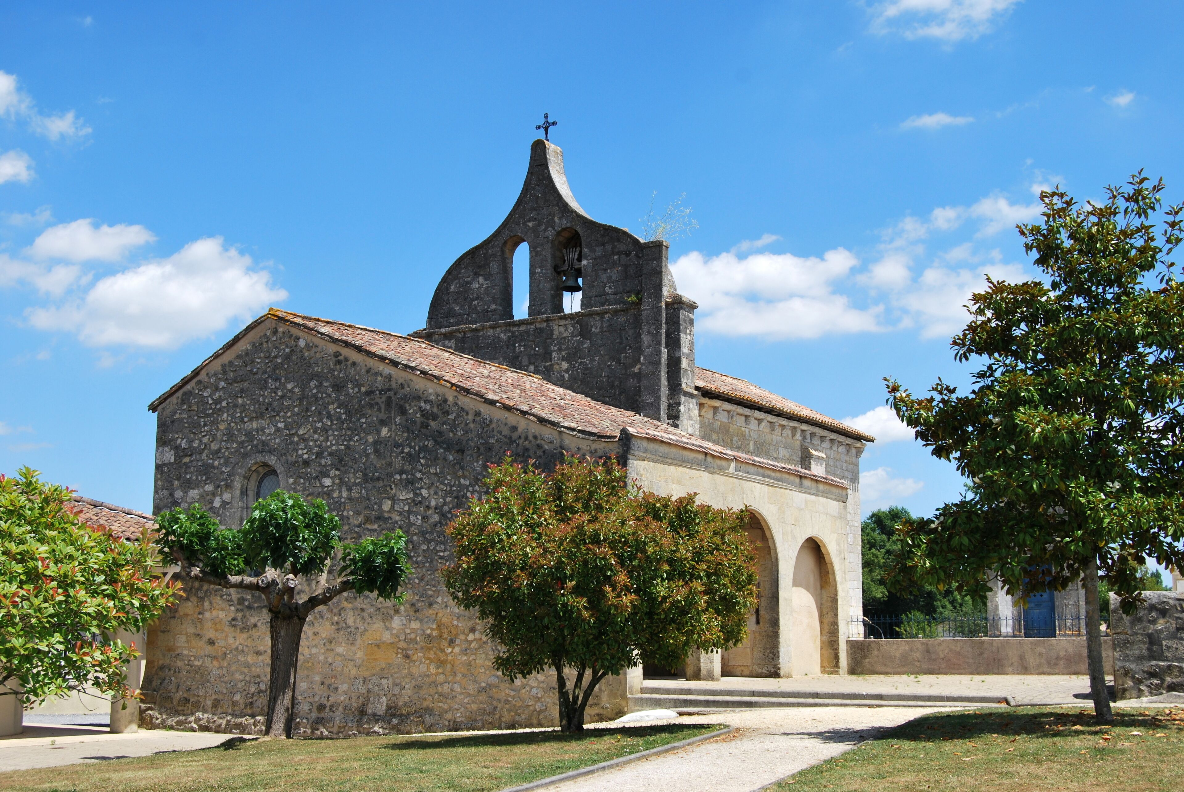 A historic stone church with a bell tower, arched windows, and a cross on top.