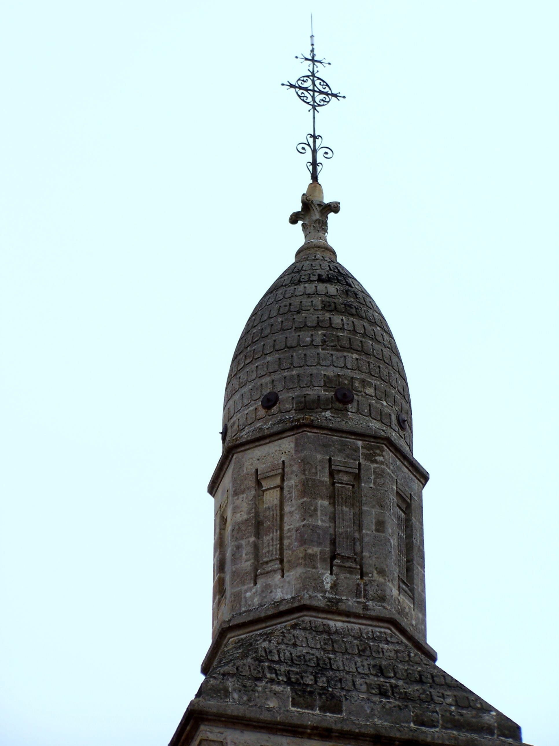 A stone tower with a brick dome and a metal weather vane.