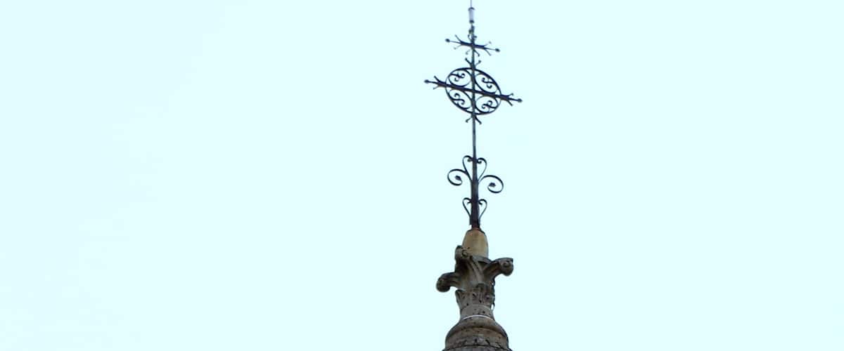A stone tower with a brick dome and a metal weather vane.