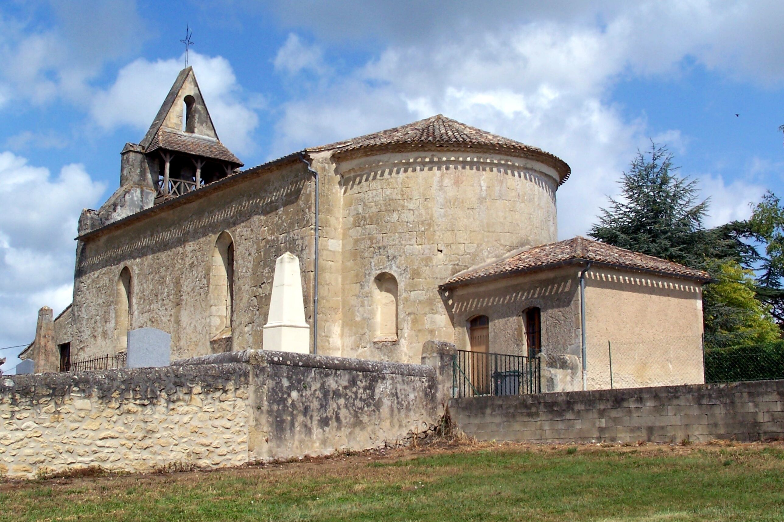 A historic stone church with a bell tower and a round tower.