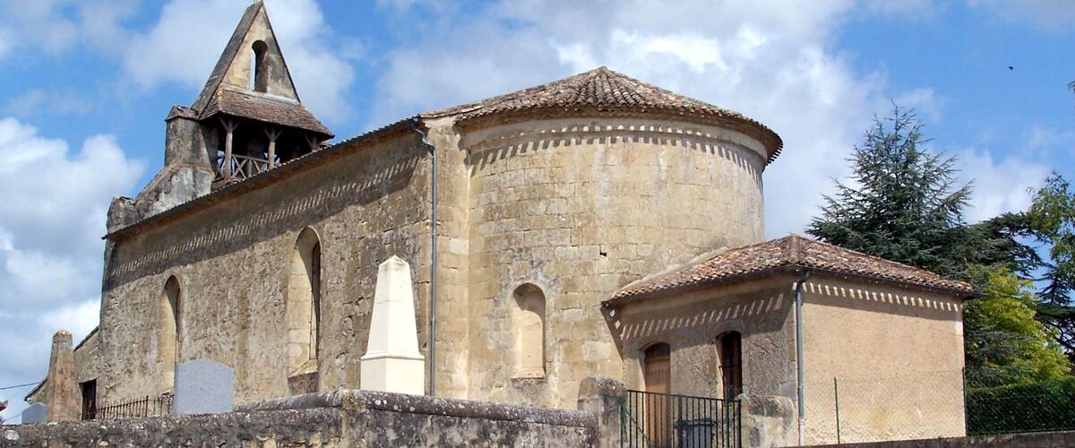 A historic stone church with a bell tower and a round tower.