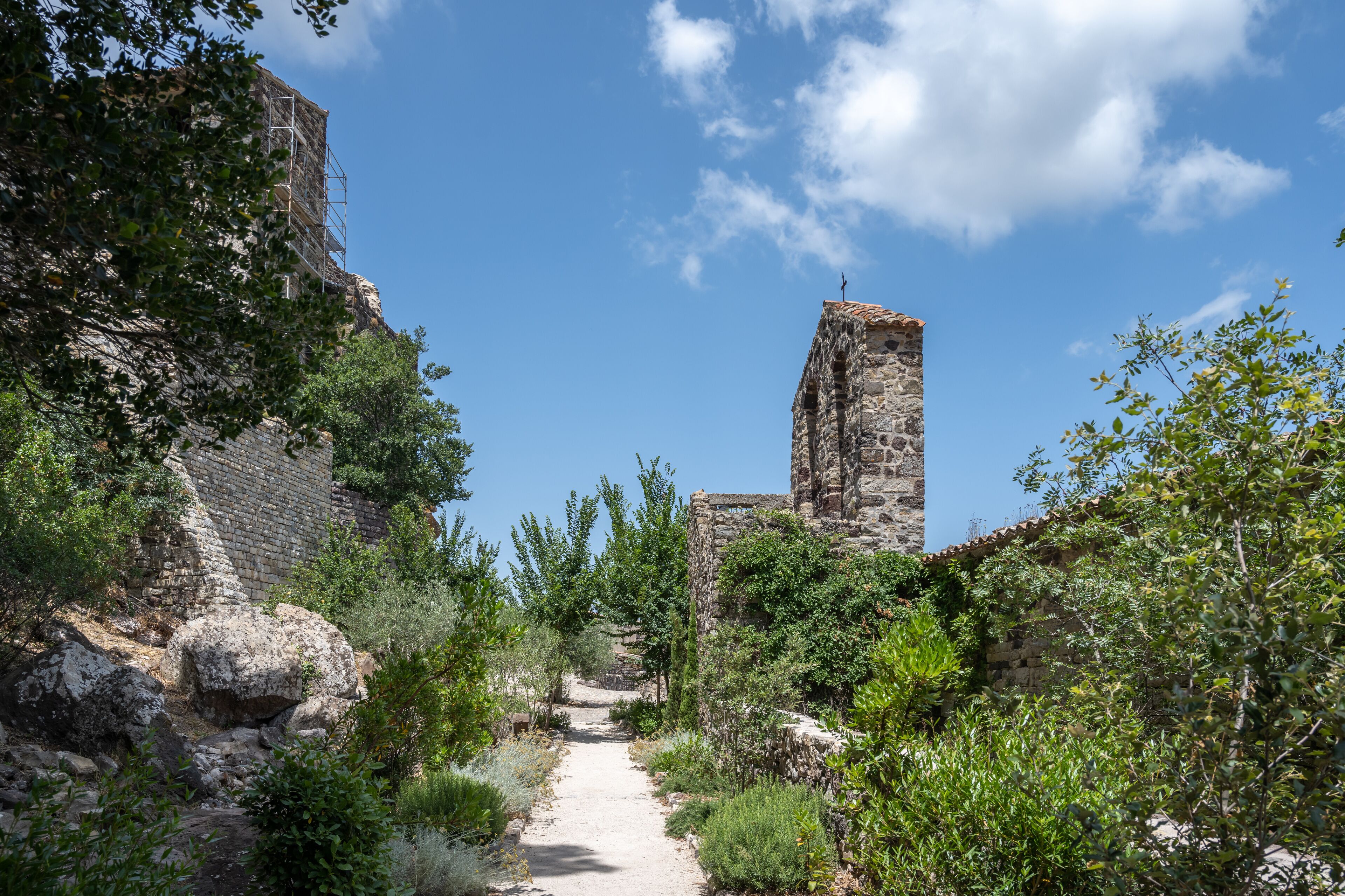 An ancient stone structure with a pathway surrounded by greenery.