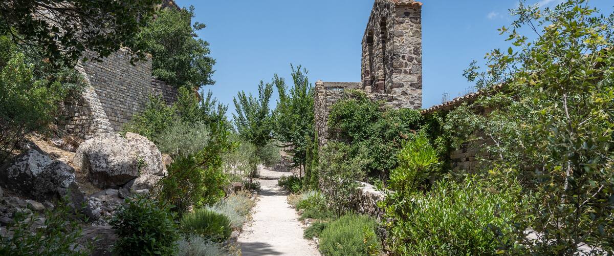 An ancient stone structure with a pathway surrounded by greenery.