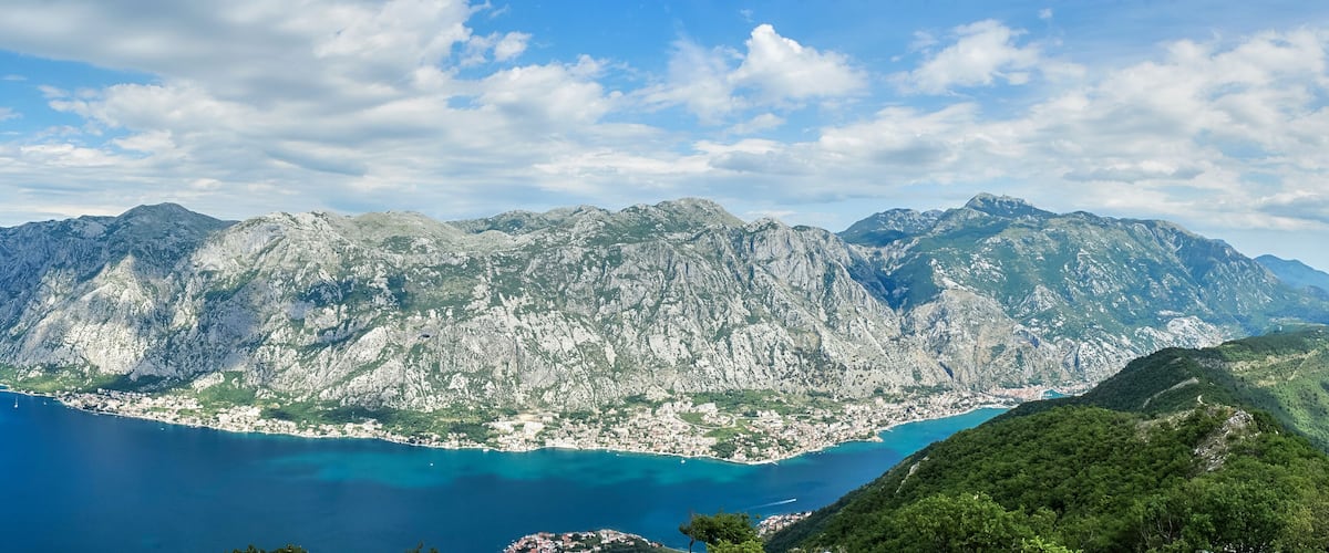 A coastal town nestled between rugged mountains with a clear blue sea.