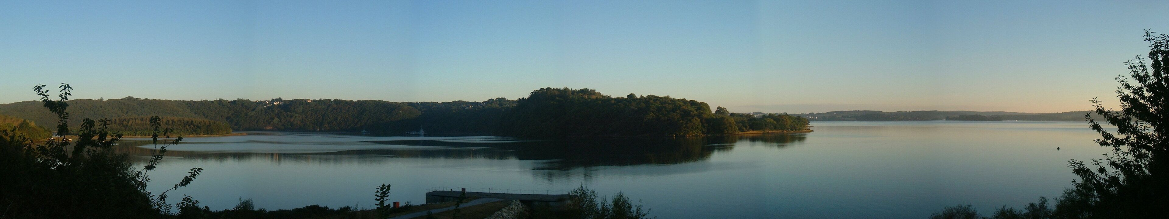 A calm lake surrounded by forested hills and a small island.