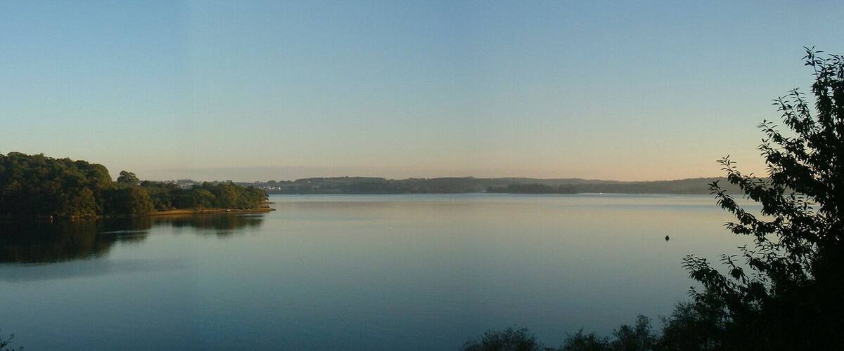 A calm lake surrounded by forested hills and a small island.