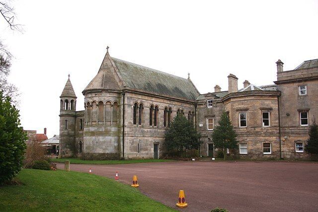 A historic stone building with a prominent tower and a large courtyard.