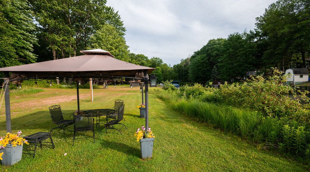 A gazebo with a table and chairs, surrounded by grass and flowers.