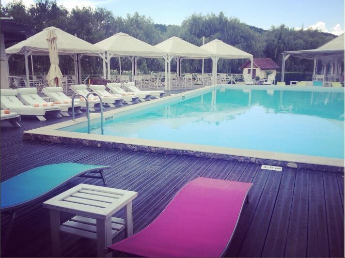 A swimming pool with lounge chairs and umbrellas.