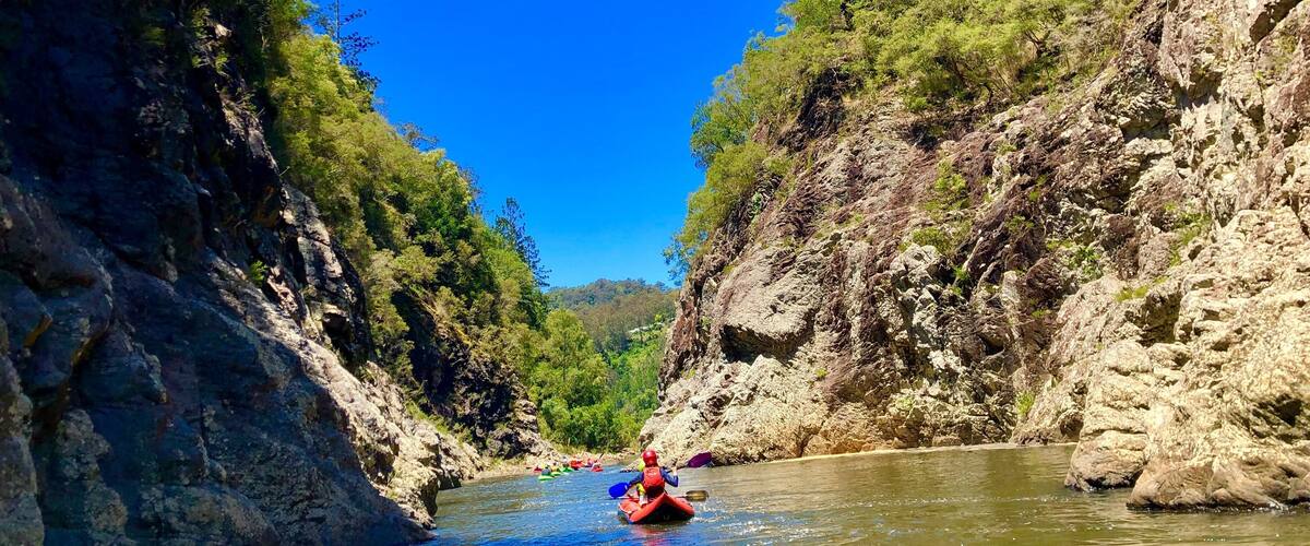 A river flanked by rocky cliffs and dense greenery.