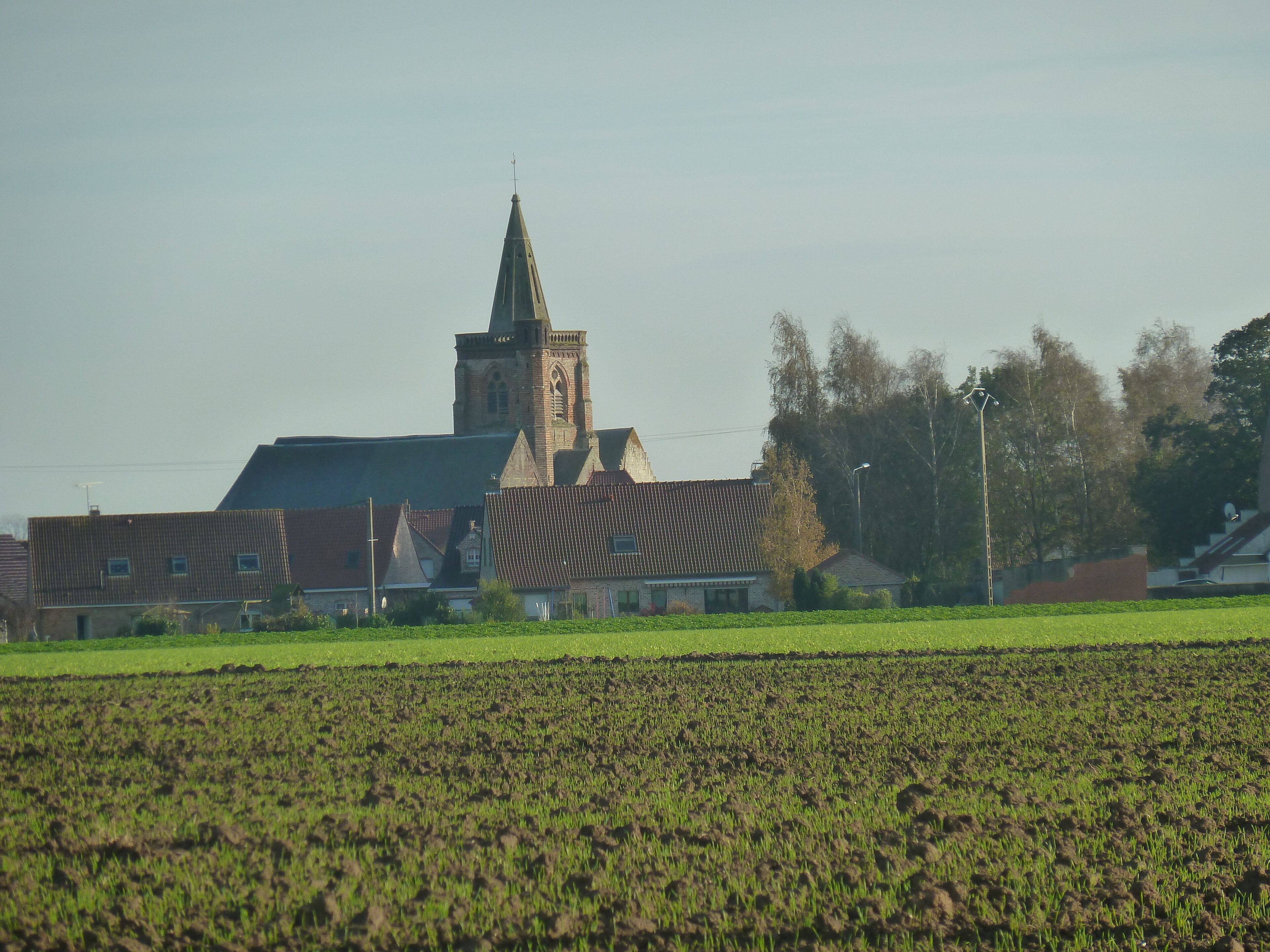 A church with a tall steeple and a field in the foreground.