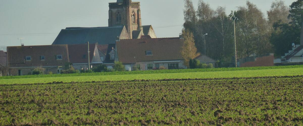 A church with a tall steeple and a field in the foreground.