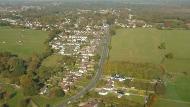 An aerial view of a residential area with houses, roads, and green fields.