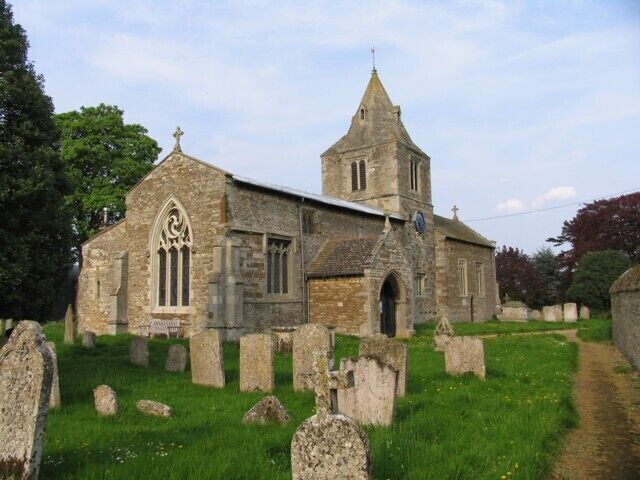 A stone church with a tall tower and a graveyard with headstones.
