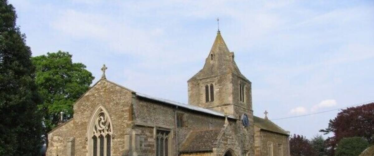 A stone church with a tall tower and a graveyard with headstones.