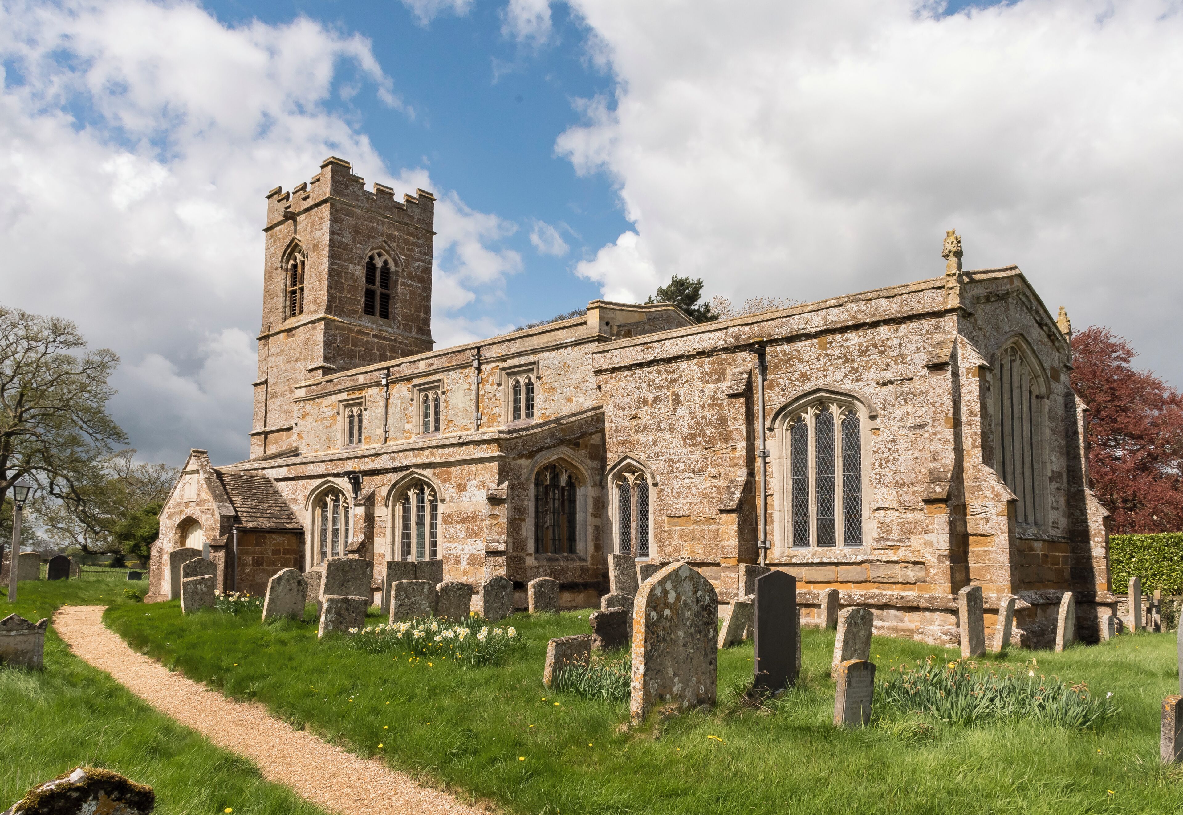 A historic church with a tall tower and a graveyard in front.