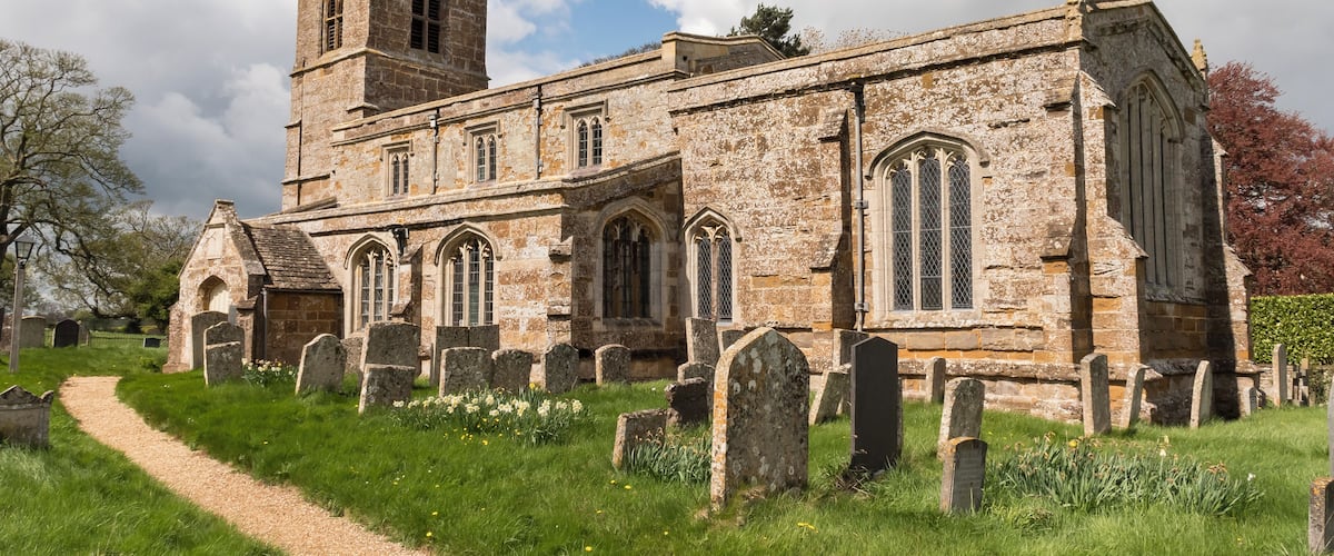 A historic church with a tall tower and a graveyard in front.